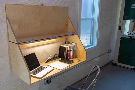 wall-mounted desk in a workshop with a laptop and books